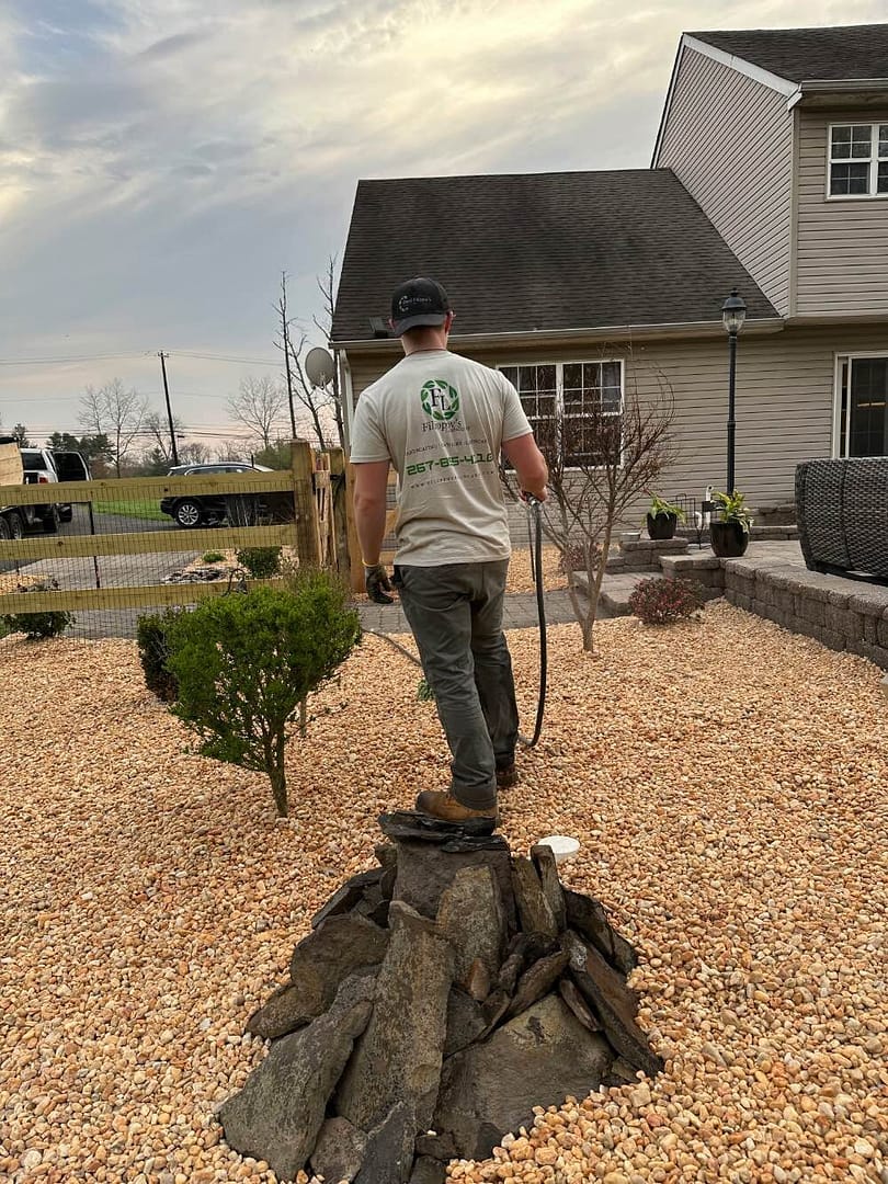 person watering bush and tree after landscaping project