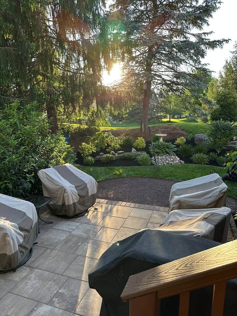 a patio with chairs and landscape design in back